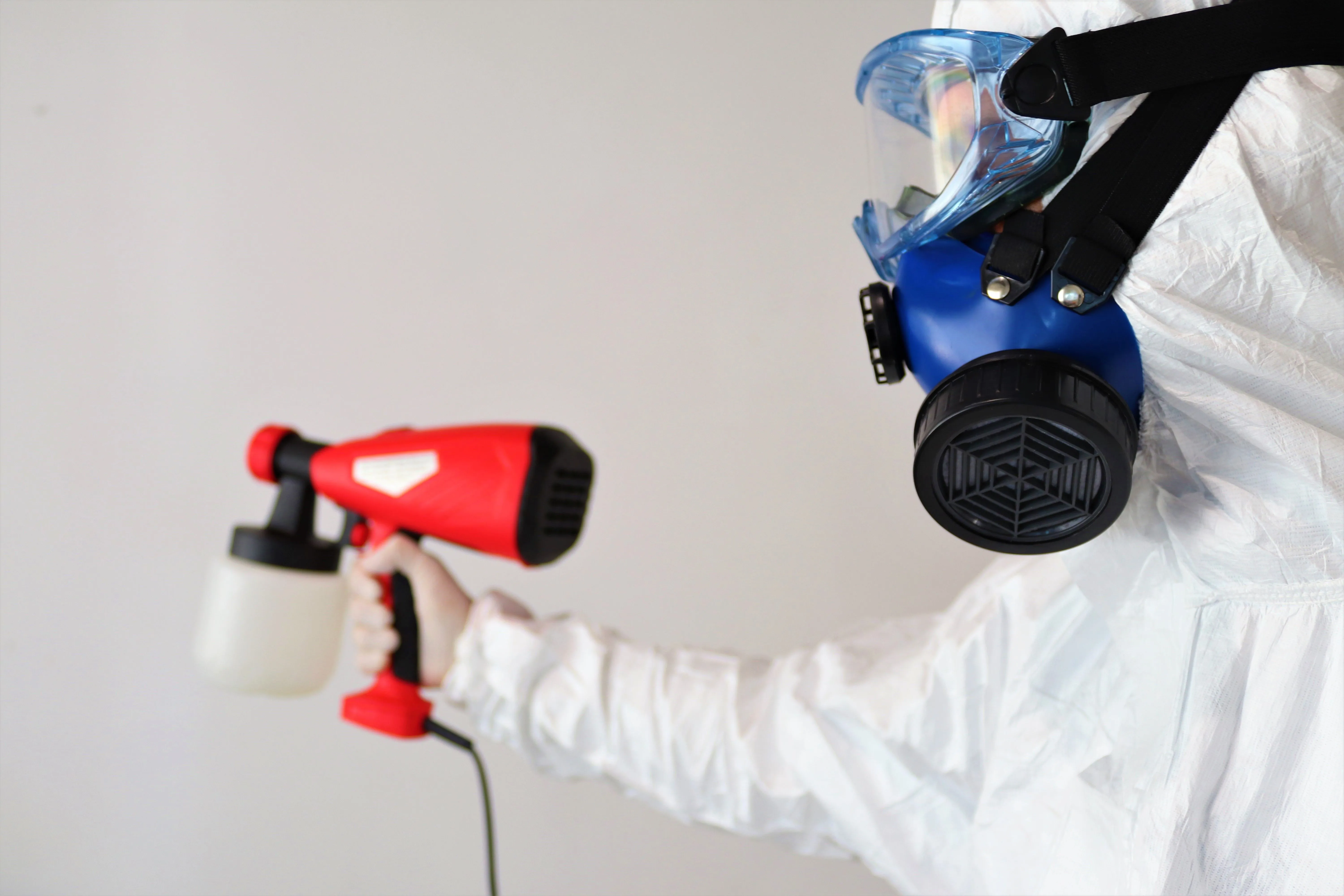 Certified remediation specialist wearing professional protective equipment setting up physical negative-pressure containment inside a mold-impacted property